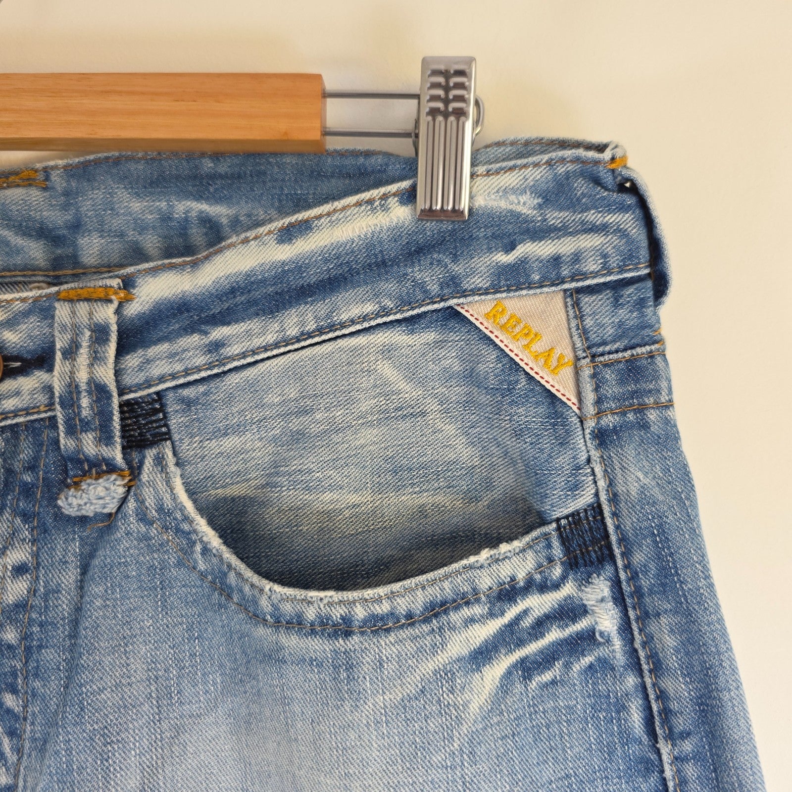 Replay blue straight jeans with button fly and light distressed pocket detailing.