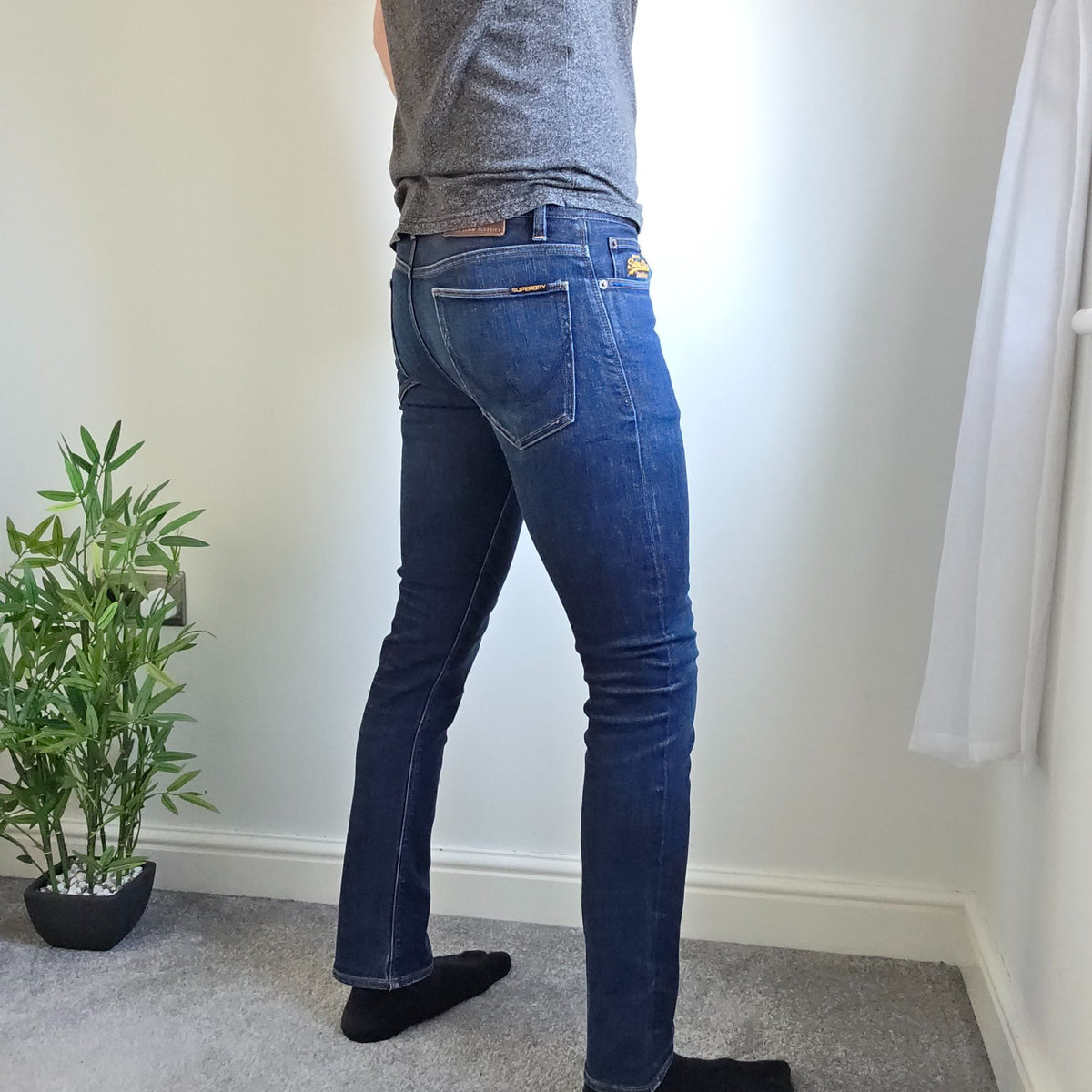 Superdry blue slim jeans with subtle fading, contrast orange stitching, and five-pocket design.