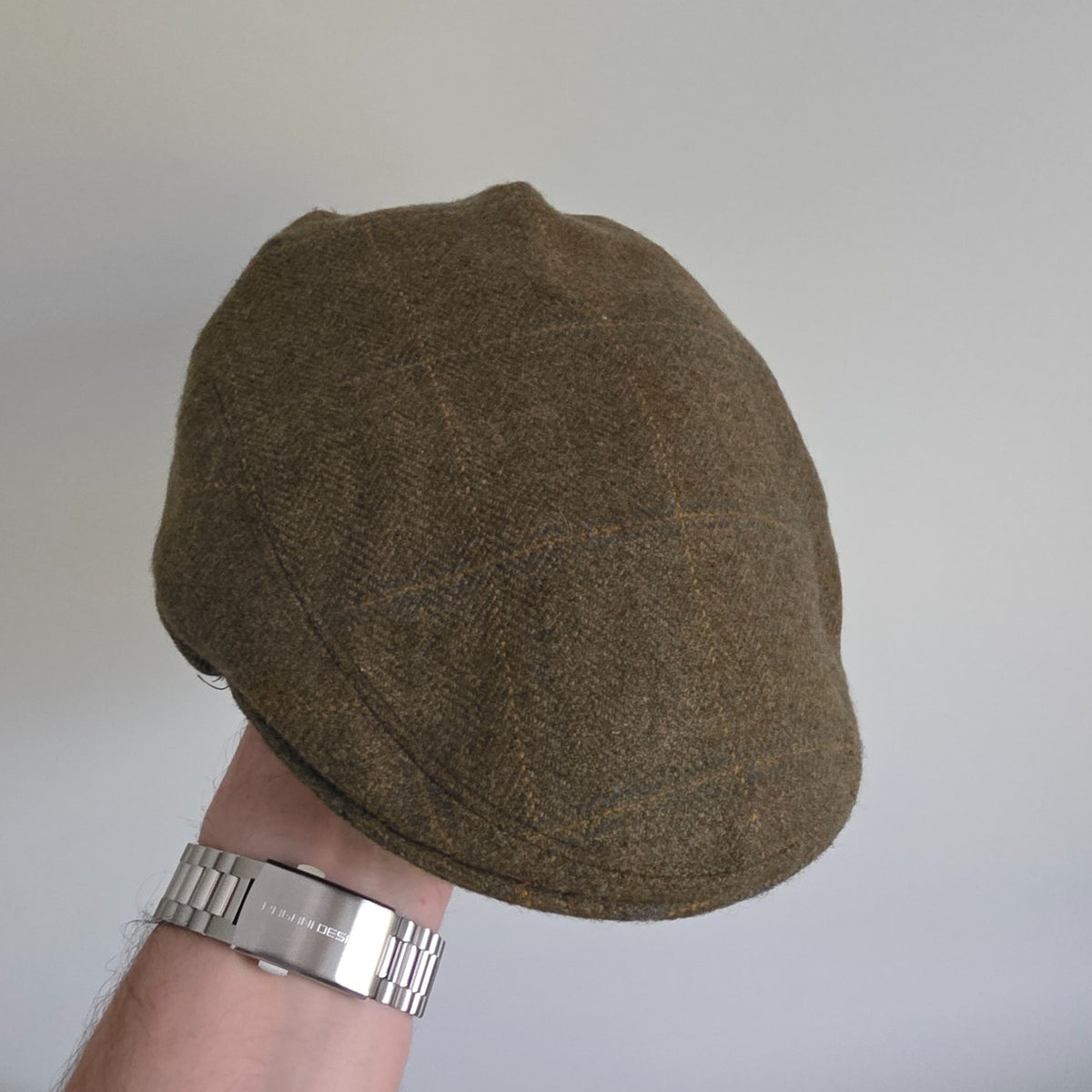 William Powell brown tweed flat cap with stitched panel construction and subtle flecks.