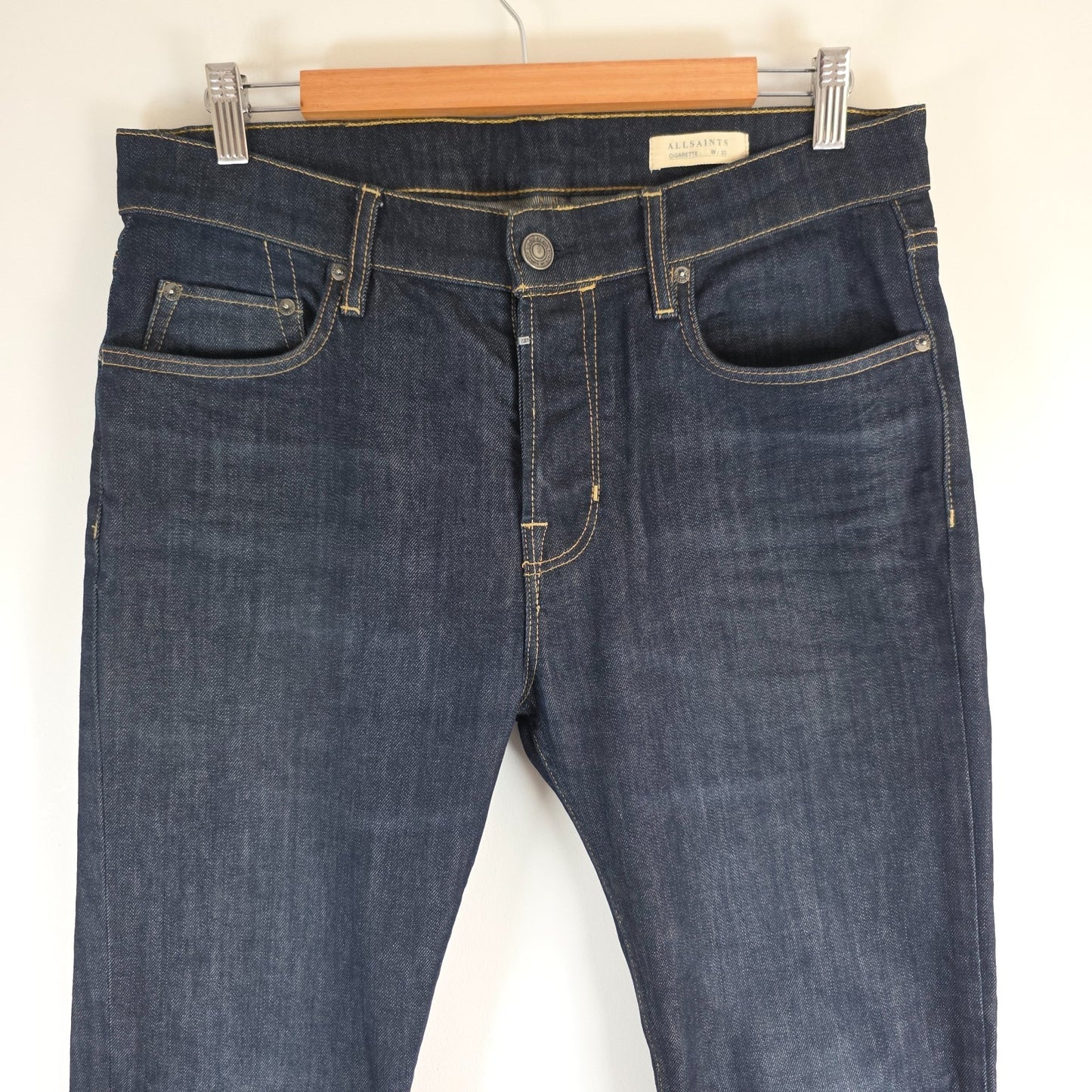 AllSaints blue skinny jeans with button fly and subtle logo detail.