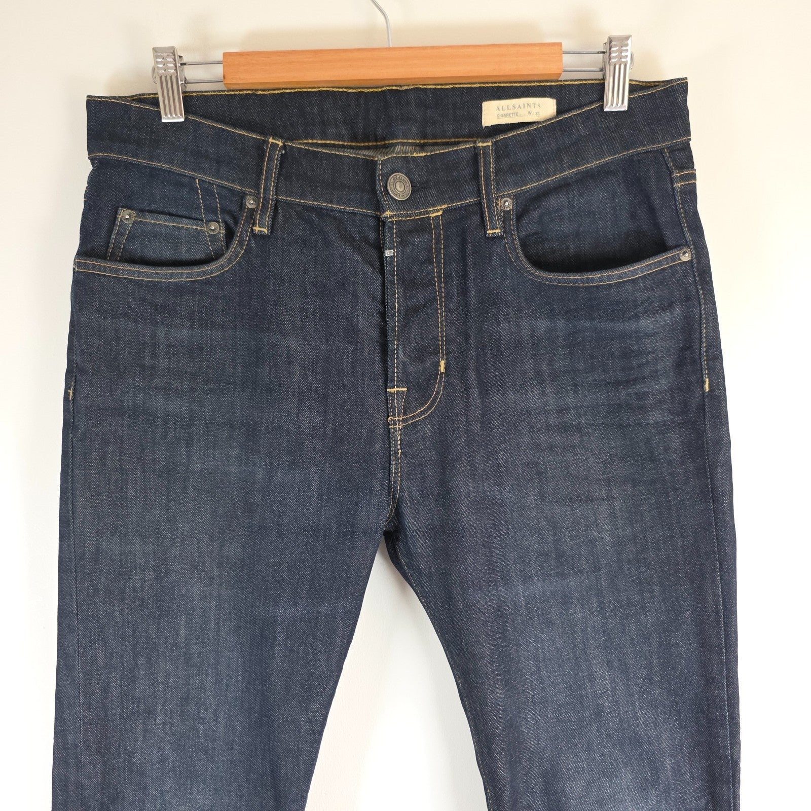 AllSaints blue skinny jeans with button fly and subtle logo detail.