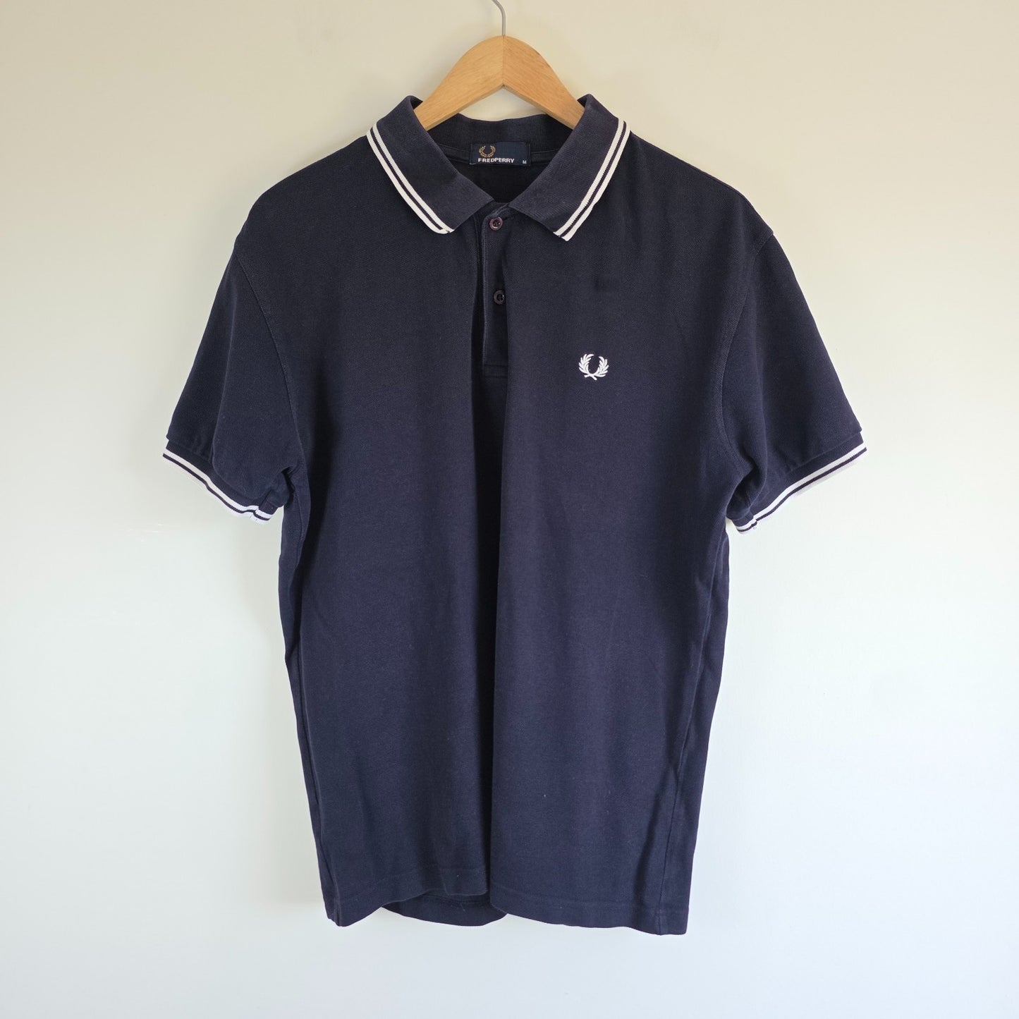 Fred Perry navy blue polo shirt with twin tipped collar and cotton material.