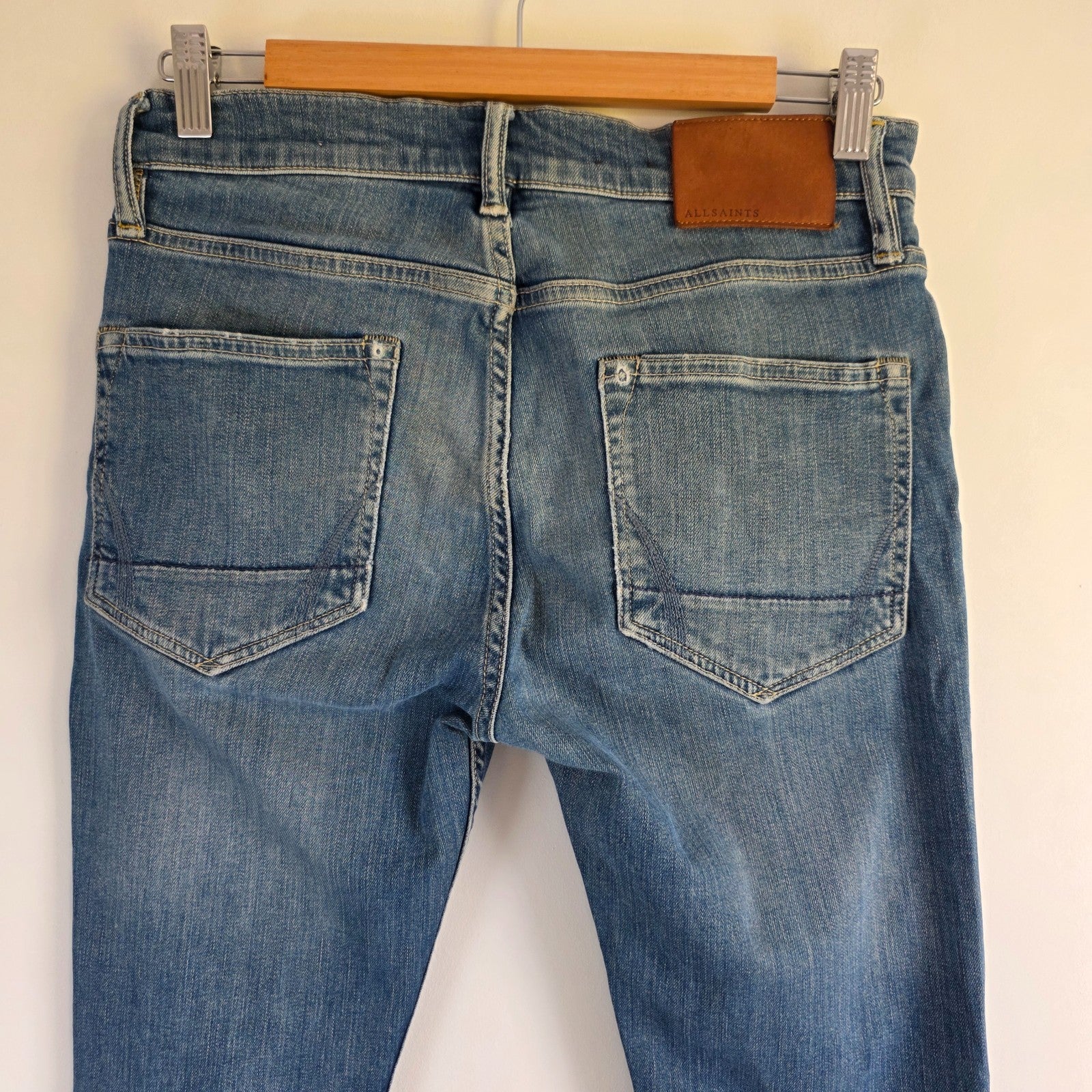 AllSaints blue skinny jeans with faded wash and modern slim fit design.