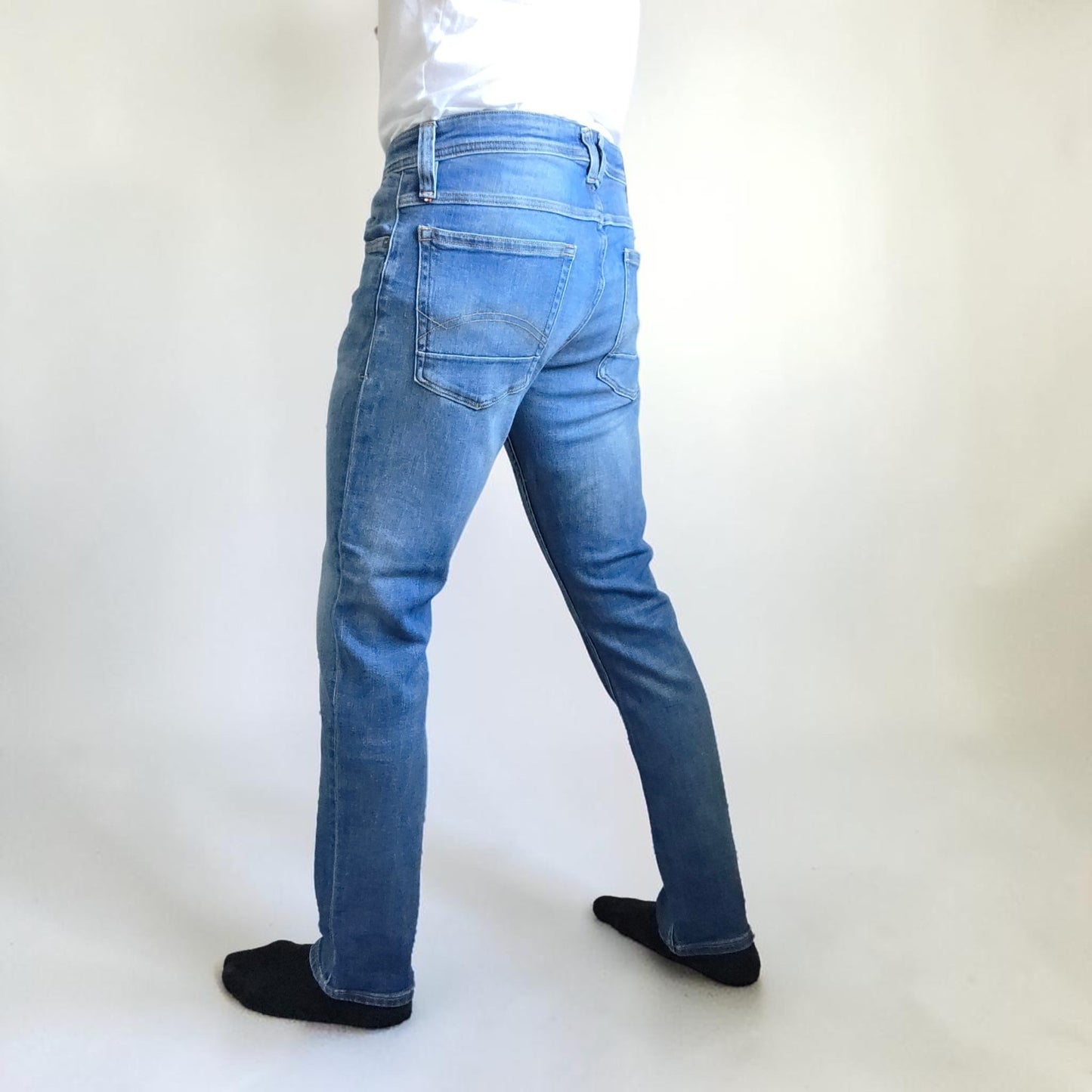 Tommy Hilfiger blue tapered jeans with stretch denim and small rip detail.