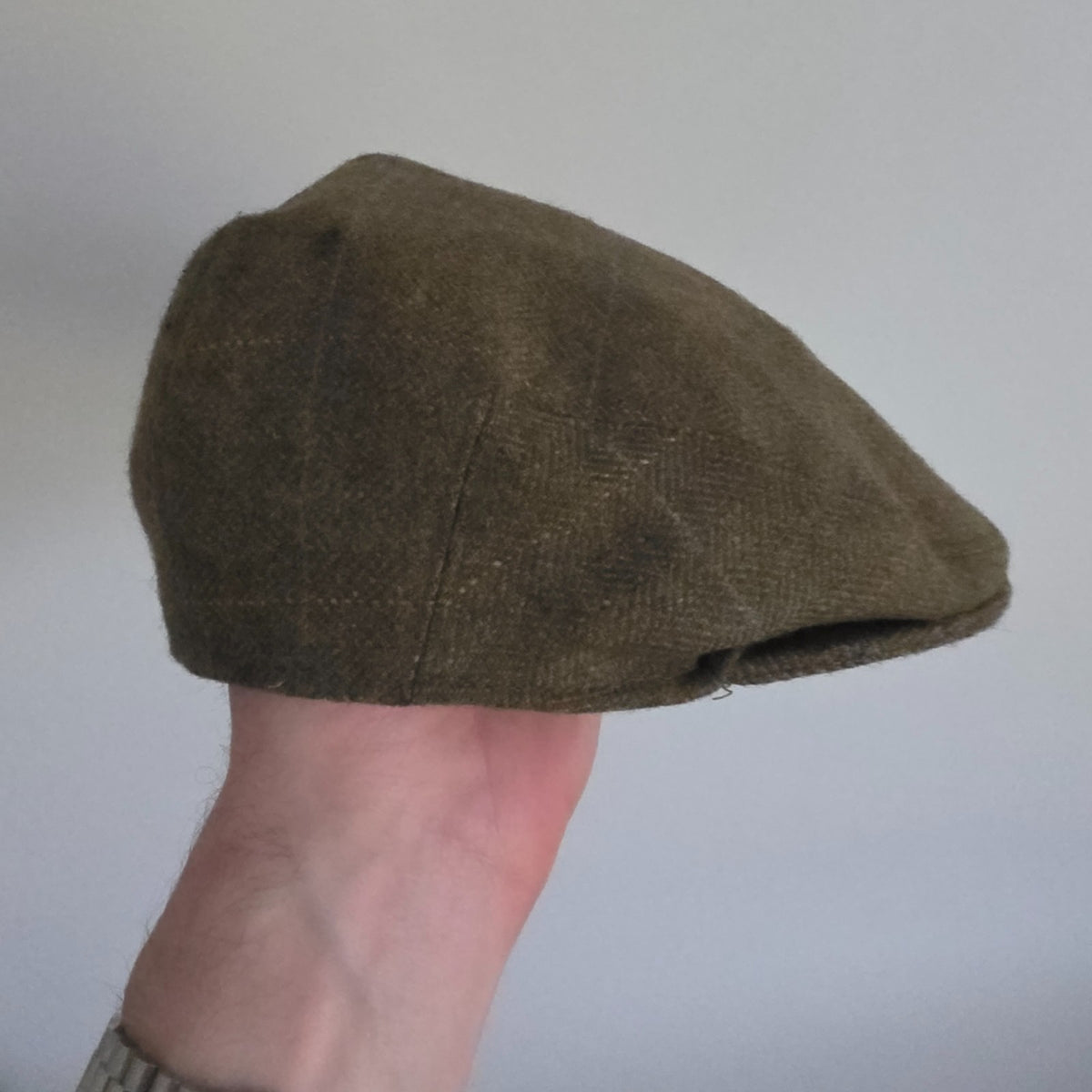 William Powell brown tweed flat cap with stitched panel construction and subtle flecks.