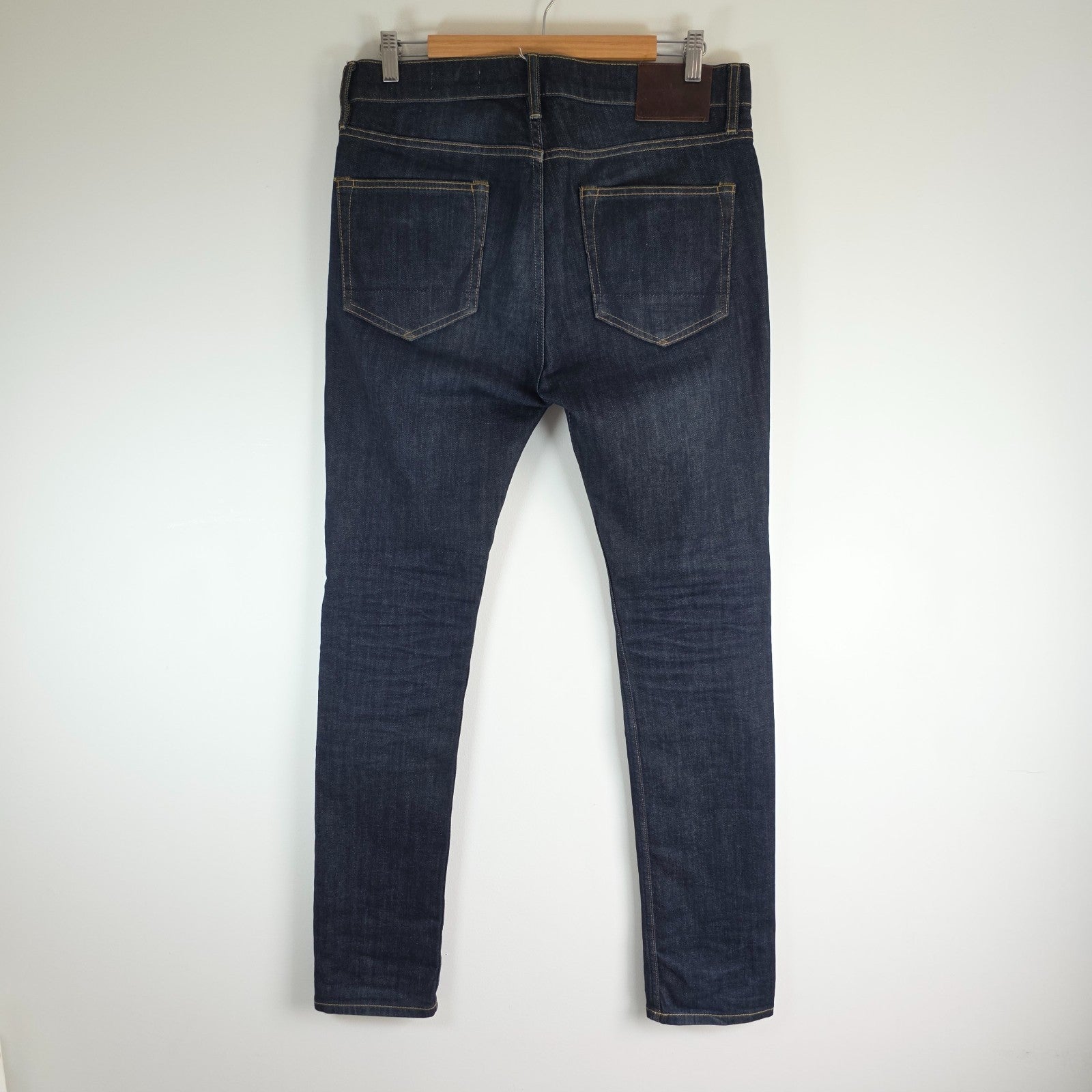 AllSaints blue skinny jeans with button fly and subtle logo detail.