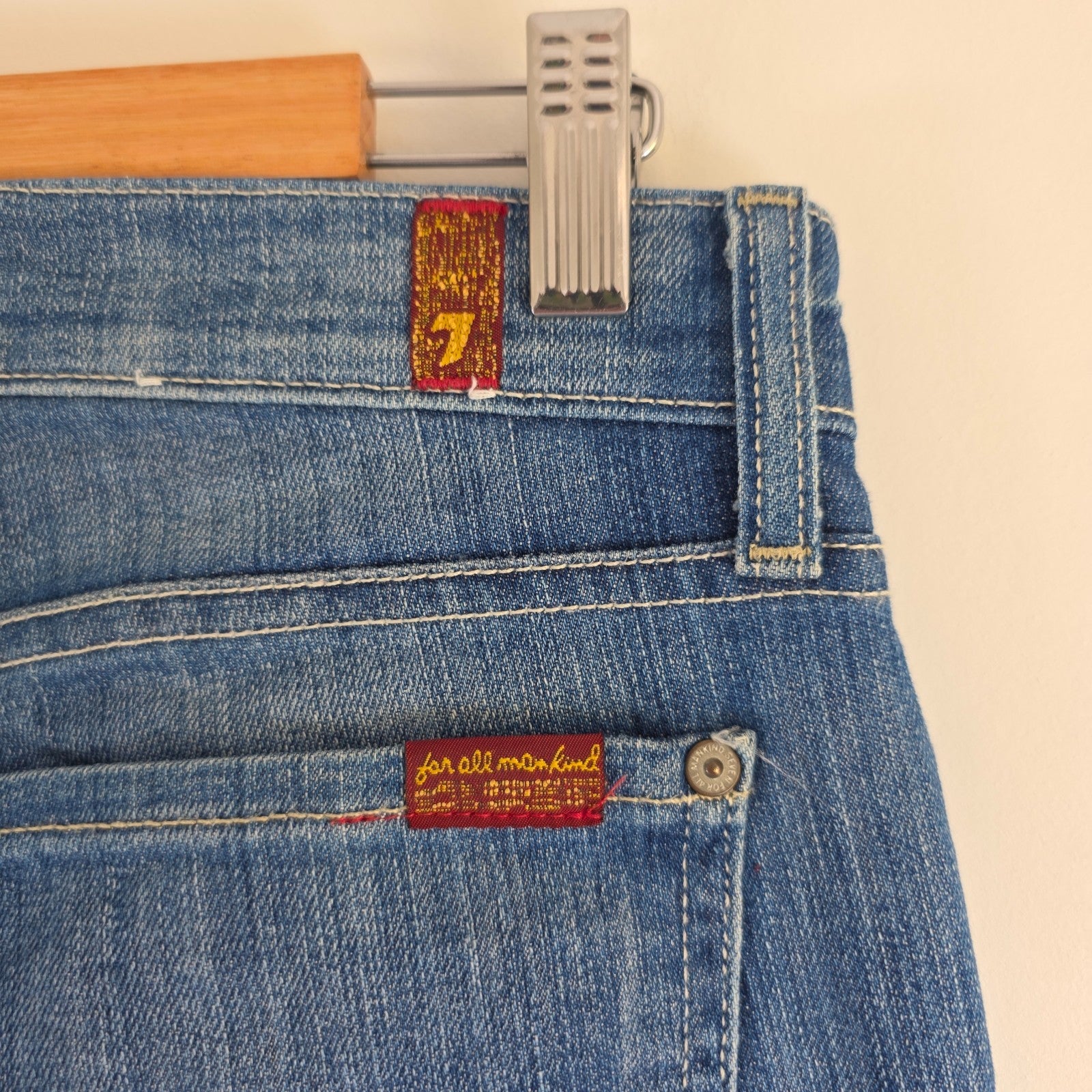 7 For All Mankind blue straight jeans with low rise and subtle branding details.