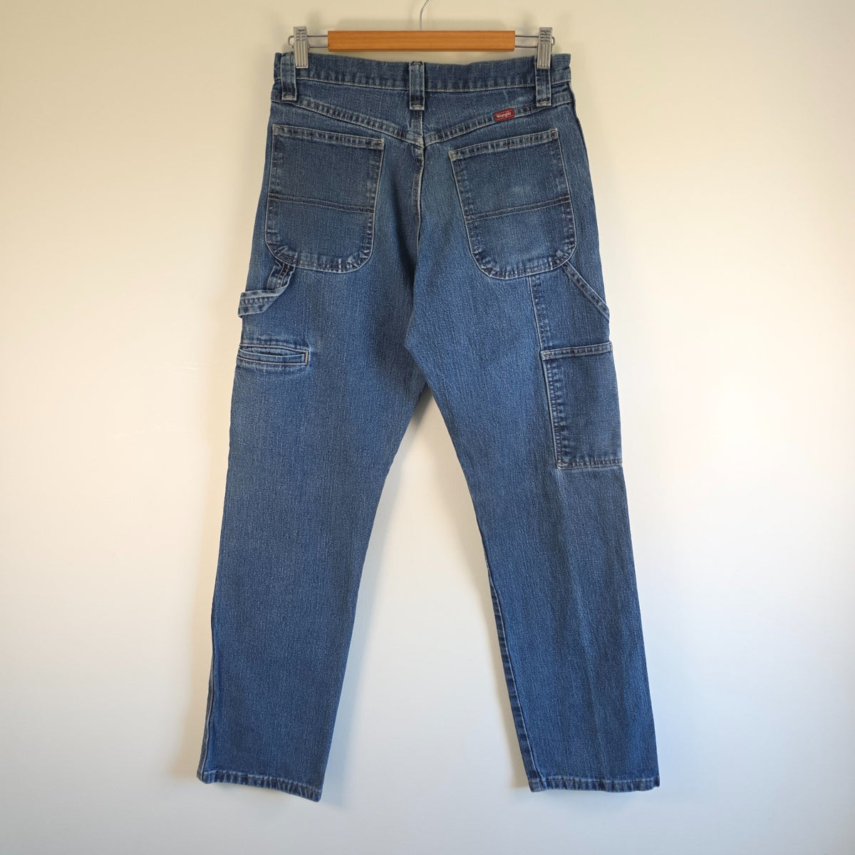 Wrangler blue carpenter jeans with distressed detailing, utility pockets, and hammer loop.