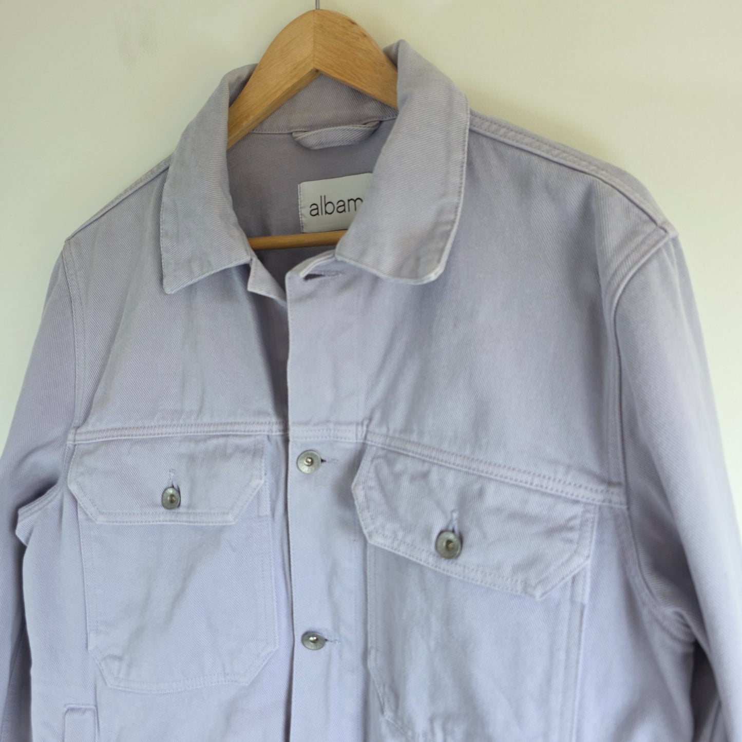 Albam lilac denim jacket with button front, chest pockets, and side pockets.