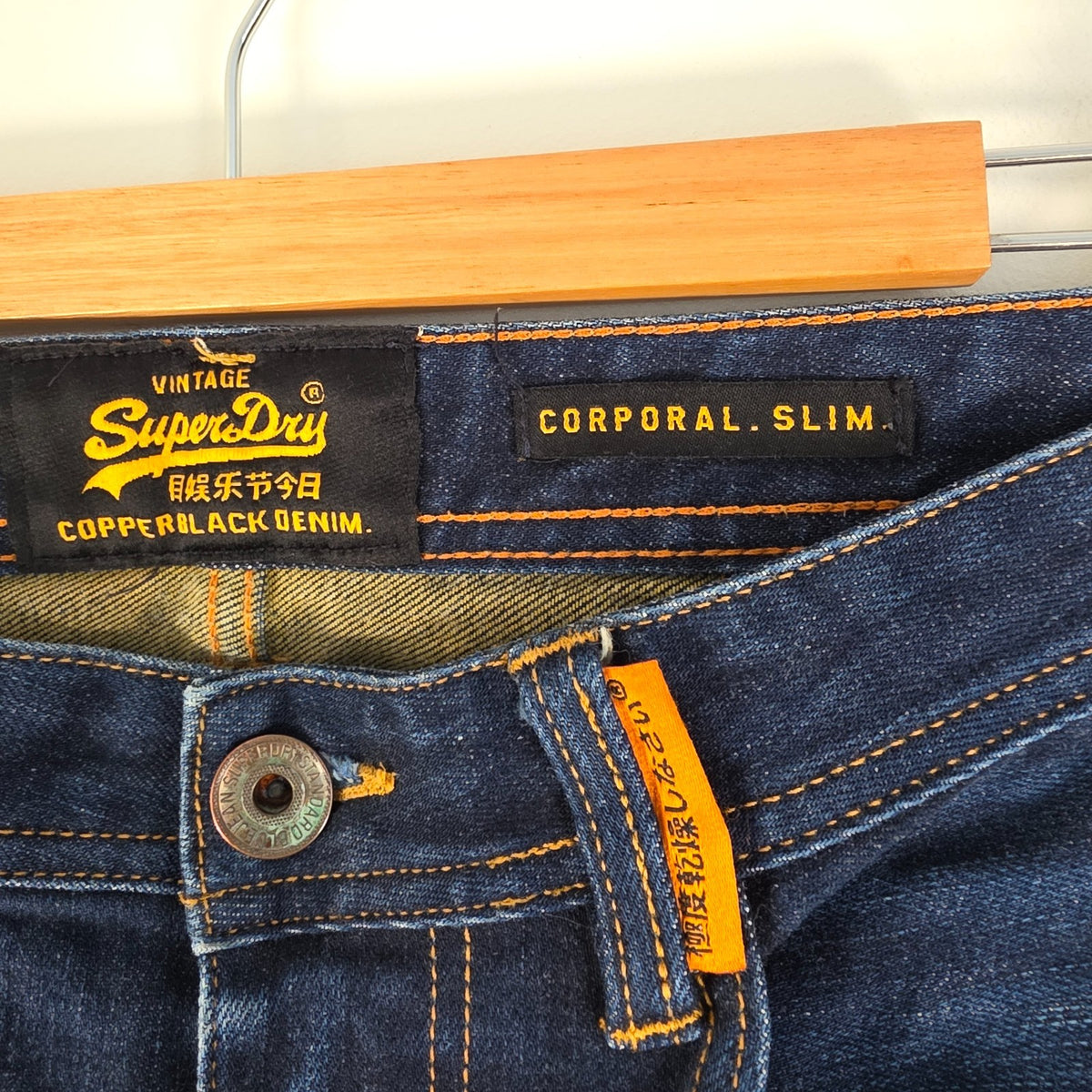 Superdry blue slim jeans with subtle fading, contrast orange stitching, and five-pocket design.