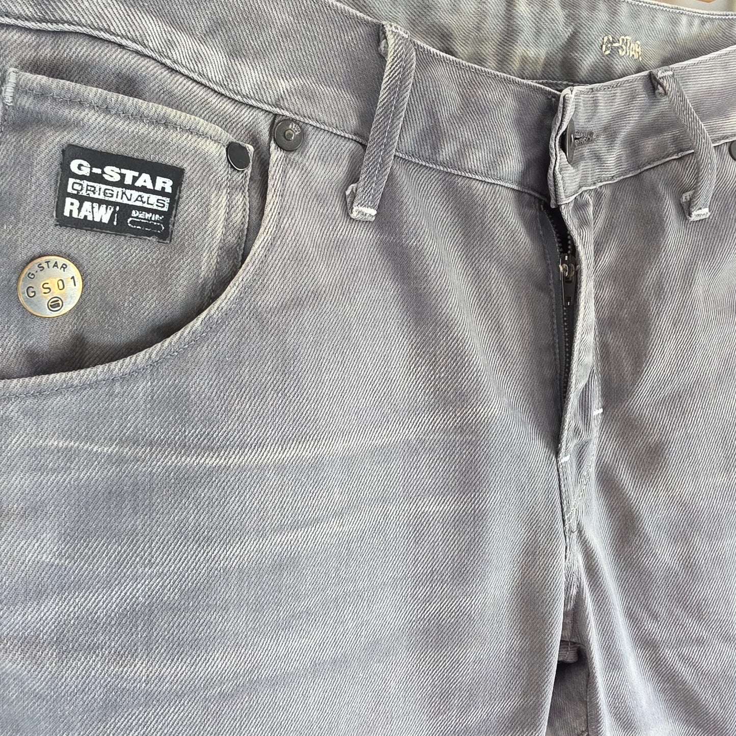 G-Star grey straight jeans with biker style detailing and subtle wear at the hem.