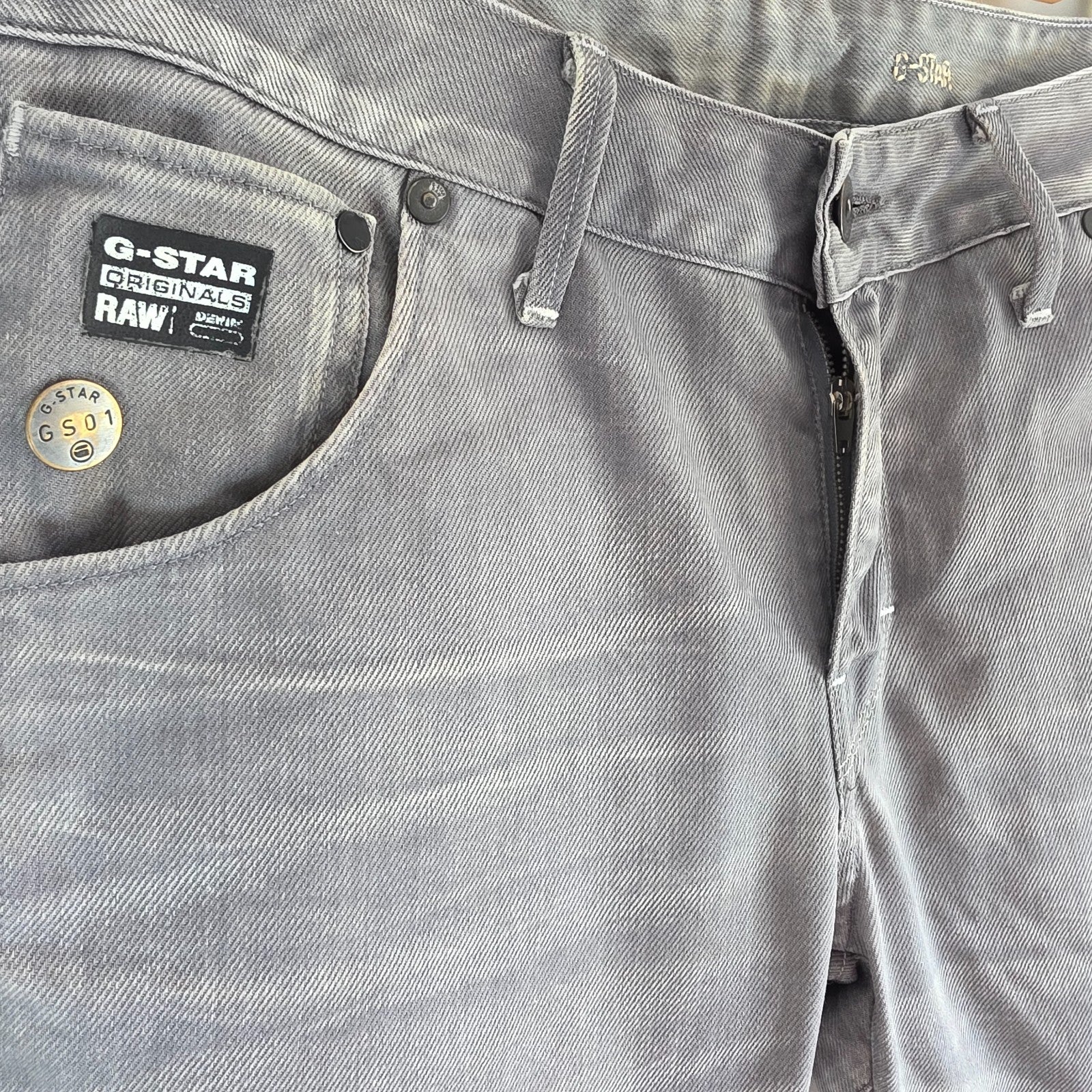G-Star grey straight jeans with biker style detailing and subtle wear at the hem.
