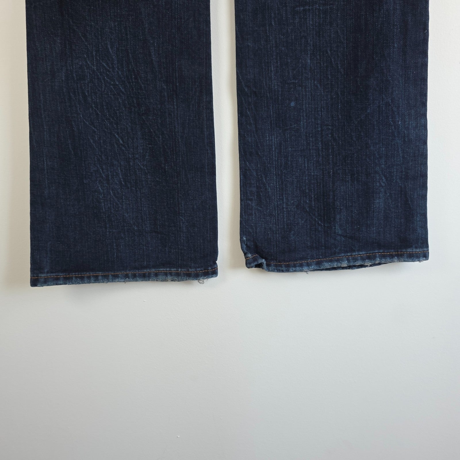Tommy Hilfiger blue bootcut jeans with logo patch and classic denim texture.