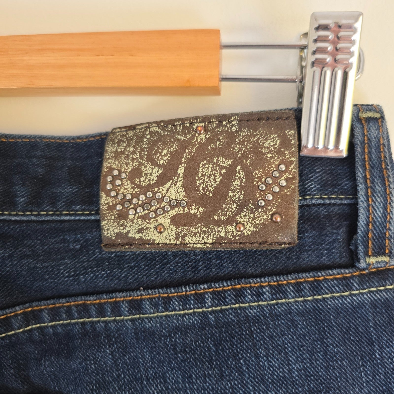 Tommy Hilfiger blue bootcut jeans with logo patch and classic denim texture.
