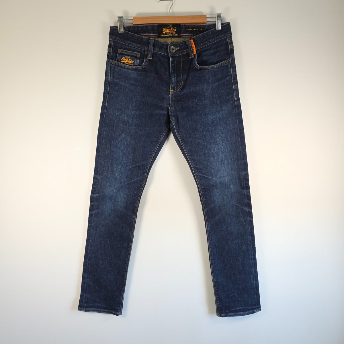 Superdry blue slim jeans with subtle fading, contrast orange stitching, and five-pocket design.