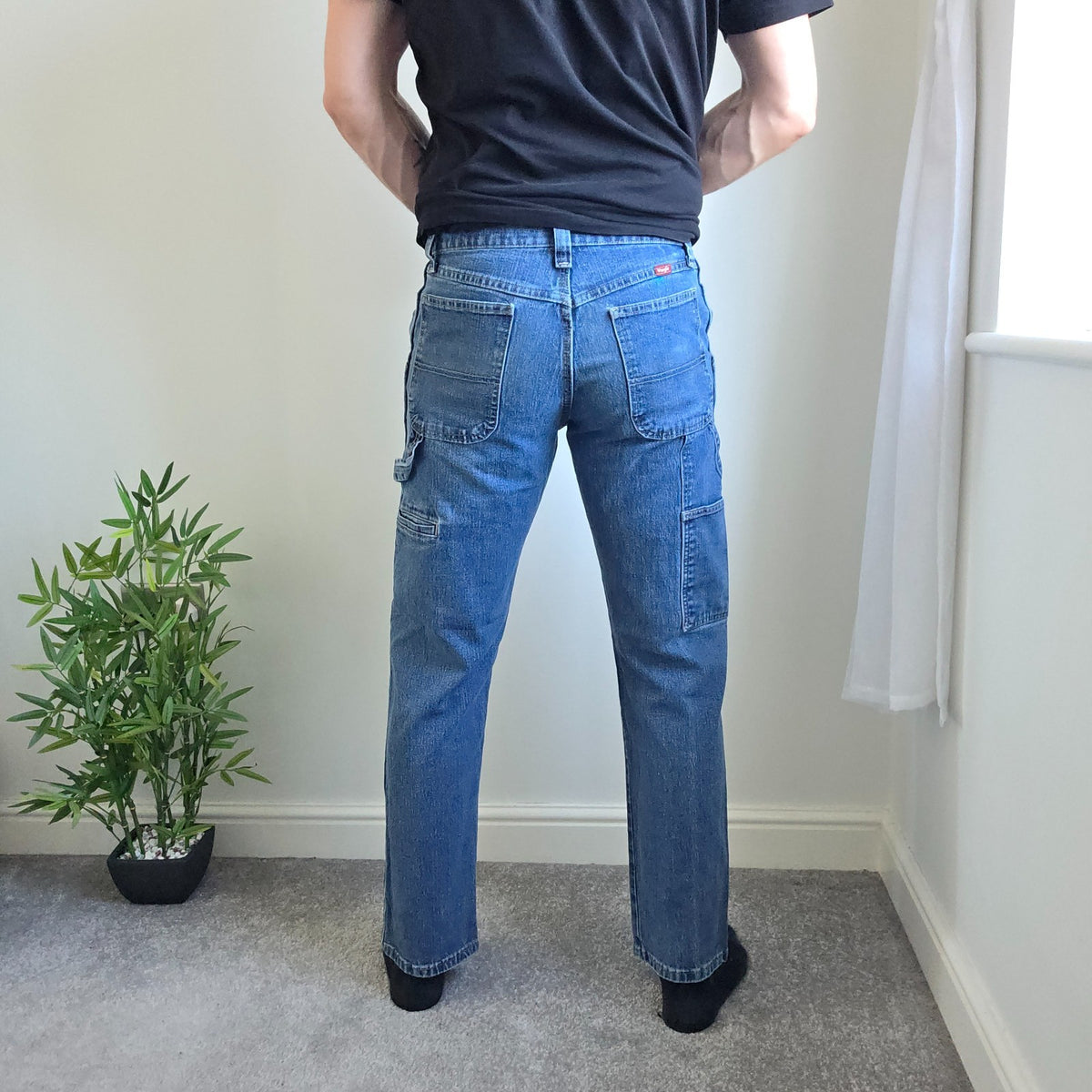 Wrangler blue carpenter jeans with distressed detailing, utility pockets, and hammer loop.